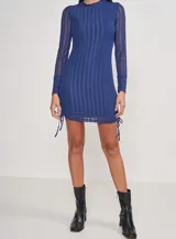 Vestido corto azul de tejido de punto con cuello alto y mangas largas. Presenta franjas verticales semitransparentes y cordones laterales ajustables.