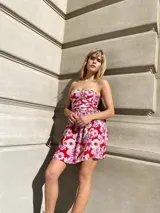 Vestido corto de gasa con estampado floral en tonos rojos, blancos y violetas. Diseño strapless con elástico en la espalda.