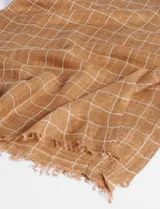 Pashmina color marrón claro con estampado de cuadrillé blanco, confeccionada en lino y poliéster.