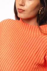 Sweater de punto acanalado color coral, con cuello alto y mangas largas con puños acampanados.