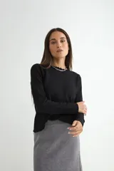 Sweater de punto negro con cuello redondo y detalle de borde ondulado, de manga larga y corte clásico.