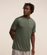 Remera deportiva masculina de manga corta con cuello redondo, confeccionada en tejido técnico con tecnología Dry para mayor transpirabilidad. Presenta detalles reflectantes en los hombros y un diseño liso en color verde melange.