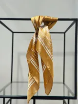 Pañuelo tipo bandana color mostaza con estampado de líneas y lunares blancos.