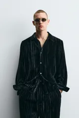 Sobrecamisa de corte relajado confeccionada en tejido de terciopelo fluido con acabado plisado. Presenta cuello solapa, cierre frontal de botones y manga larga con puños abotonados.