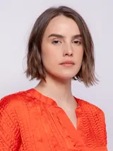 Blusa de manga corta con escote en V, confeccionada en tela satinada con textura de pliegues horizontales.