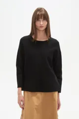 Sweater negro liso, holgado, con cuello a la base y broches decorativos en el lateral.