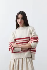 Polera de tejido de punto con diseño a rayas horizontales en color azul marino sobre base beige. Presenta cuello alto, mangas largas con puños acanalados y una silueta relajada.