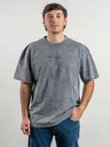 Remera de corte oversize color marrón con efecto lavado, cuello redondo y estampa frontal con la frase 'URUGUAY noma!'.