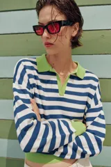 Sweater de punto a rayas horizontales en azul y blanco, con cuello polo verde lima, escote en V y detalles en verde lima en los puños y el borde inferior.