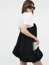 Vestido corto negro, estilo globo o balloon, con escote corazón pronunciado. Se lleva sobre una remera blanca de manga corta.