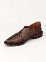 Mocasines de charol color bordó, de diseño vanguardista con corte asimétrico en el empeine, abertura en V, punta fina y suela plana con pequeño tacón.