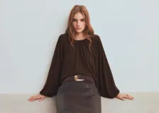 Blusa de color marrón chocolate con cuello redondo, diseño fruncido en la parte superior y mangas largas abullonadas con puños elásticos.