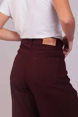 Pantalón de corte wide leg confeccionado en pana acanalada color marrón chocolate. Presenta tiro alto, cierre frontal con botón y bolsillos laterales.
