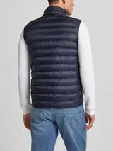 Chaleco acolchado azul marino de nailon reciclado, con cuello alto, cierre de cremallera, bolsillos laterales y logo de Tommy Hilfiger bordado en el pecho.