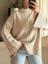 Sweater de punto oversize color beige, con cuello redondo, mangas largas acampanadas y detalles de bordado artesanal en relieve a lo largo del frente y las mangas.