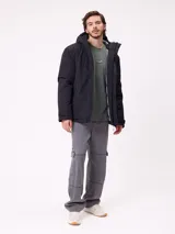 Campera técnica de invierno marca Rusty, color negro, con capucha ajustable, cierre frontal con solapa y bolsillos laterales. Presenta logo de la marca estampado en blanco en la manga y en el pecho.