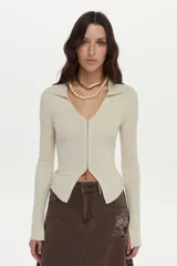 Cardigan tejido en rib con hilado de lurex, color crudo, calce al cuerpo, cuello polo, mangas largas con aberturas y cierre metálico frontal bidireccional.