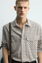 Camisa de corte relajado con estampado de cuadros, cuello solapa, manga larga con puños abotonados y bolsillos frontales de plastrón con solapa. Cierre frontal con botones a presión.