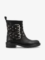Bota corta de cuero negro con punta redonda y suela plana. Presenta dos tiras horizontales decoradas con ojales metálicos y hebillas grandes de metal plateado.