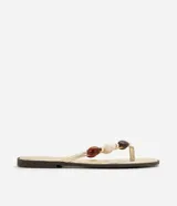 Sandalias planas tipo mule de dedo de la marca Satinato, en color dorado con plantilla metalizada y suela baja. Presenta una tira con aplicaciones decorativas de cuentas de resina en tonos marrones y marfil.