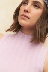 Top tejido de punto color coral, de cuello alto y sin mangas, corte ajustado.