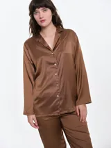 Camisa de dormir de satén con cuello solapa y cierre frontal de botones. Presenta mangas largas, corte holgado y un pequeño bordado en el pecho.