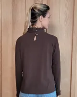 Polera de manga larga color blanco, confeccionada en algodón, con cuello alto tipo tortuga y detalles de volados en el cuello y en los puños.