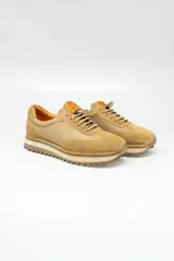 Championes de cuero color beige, de estilo casual, con cordones elastizados y suela de goma.