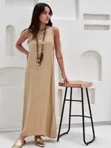 Vestido negro largo de tela satinada, sin mangas y con cuello redondo.