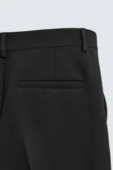 Pantalón de corte wide fit y largo cropped, confeccionado en tejido con elasticidad. Presenta cintura con pliegues frontales, bolsillos laterales y bolsillos traseros de vivo. Cierre frontal con cremallera y botón.