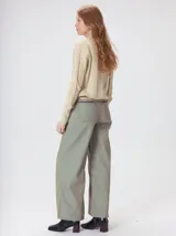 Sweater de punto color beige con cuello alto, detalles de paneles verticales texturizados y monograma bordado en el pecho.