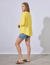Blusa amarilla de tejido acanalado con cuello redondo, escote en V y aplique metálico. Manga ¾.