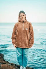 Buzo beige de corte clásico con cuello alto y cierre parcial con cremallera.