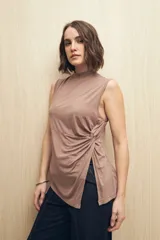 Top sin mangas color marrón topo, con cuello alto y detalle de nudo drapeado en el lateral que genera una abertura asimétrica en el ruedo.