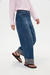 Pantalón jean de corte baggy y tiro medio, con diseño amplio y dobladillo vuelto que deja ver un detalle estampado en el interior.