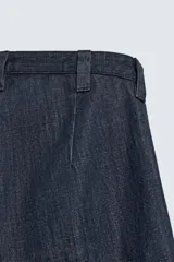 Pantalón de corte barrel fit confeccionado en denim de algodón rígido color azul oscuro. Presenta cintura con pliegues frontales, bolsillos laterales y bolsillos traseros de vivo. Cierre frontal con cremallera y gancho metálico oculto.