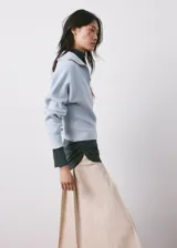 Jersey de punto celeste con cuello polo, escote en V y mangas largas con puños ajustados.