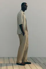 Pantalón de algodón color beige, estilo casual con corte relajado, cintura elástica con cordón de ajuste oculto y bolsillos al bies y traseros.