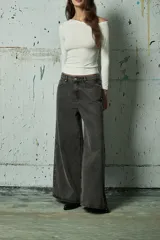 Jean de corte wide leg en color gris lavado, con diseño de aberturas laterales decoradas con tachas metálicas a lo largo de toda la pierna.