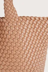 Bolso tipo tote de gran tamaño con diseño trenzado en color tostado. Cuenta con dos asas superiores trenzadas y un pequeño neceser a juego colgando de una de las asas.