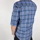 Camisa de manga corta con cuello italiano, a cuadros grandes en tonos grises y celestes. Tiene un logo bordado en el pecho. Confeccionada en algodón 100%.