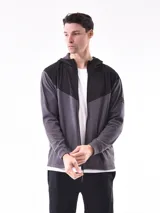 Campera deportiva con cierre frontal, capucha y diseño de bloques de color. La parte superior (hombros y capucha) es negra, y el cuerpo y mangas son de color azul vibrante, con un corte diagonal que separa ambos colores.