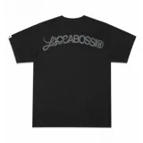 Remera de algodón color negro con estampado serigráfico en tono gris oscuro en la parte posterior. Presenta cuello reforzado, costuras reforzadas y una pequeña etiqueta decorativa en la manga.
