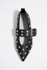 Bailarinas negras de cuero con punta fina, tachas plateadas y tira ajustable con hebilla metálica.