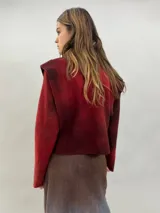 Buzo de lana merino afieltrada con diseño artesanal de efecto degradado en tonos violeta y fucsia. Presenta cuello alto, hombreras marcadas y corte holgado.