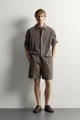 Bermuda de lino negro de corte relaxed fit, con cintura elástica ajustable mediante cordón y bolsillos frontales.