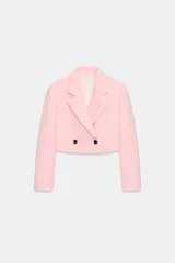 Blazer corto rosado con cuello solapa, hombreras y mangas largas. Cuenta con cierre cruzado delantero con dos botones oscuros y un bolsillo de ojal en el pecho.