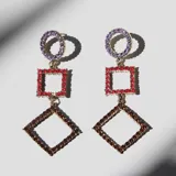 Aros colgantes con base metálica dorada y cristales facetados. Diseño geométrico con círculo de cristales lilas, cuadrado de cristales rojos y rombo de cristales marrones.