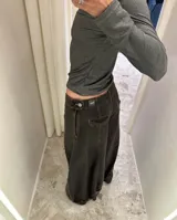 Jean de corte wide leg con efecto degradado en tonos marrón y negro. Presenta costuras verticales frontales y un diseño de puño ajustable en el bajo de la pierna.