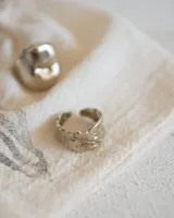 Anillo de metal macizo color plateado con forma orgánica irregular y superficie texturizada.